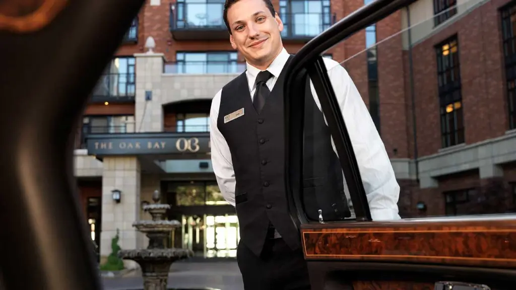 A five star hotel bellboy opening the door of a luxury car with chauffeur for a customer