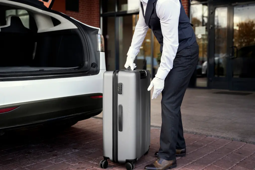 side view bellboy putting luggages in car trunk